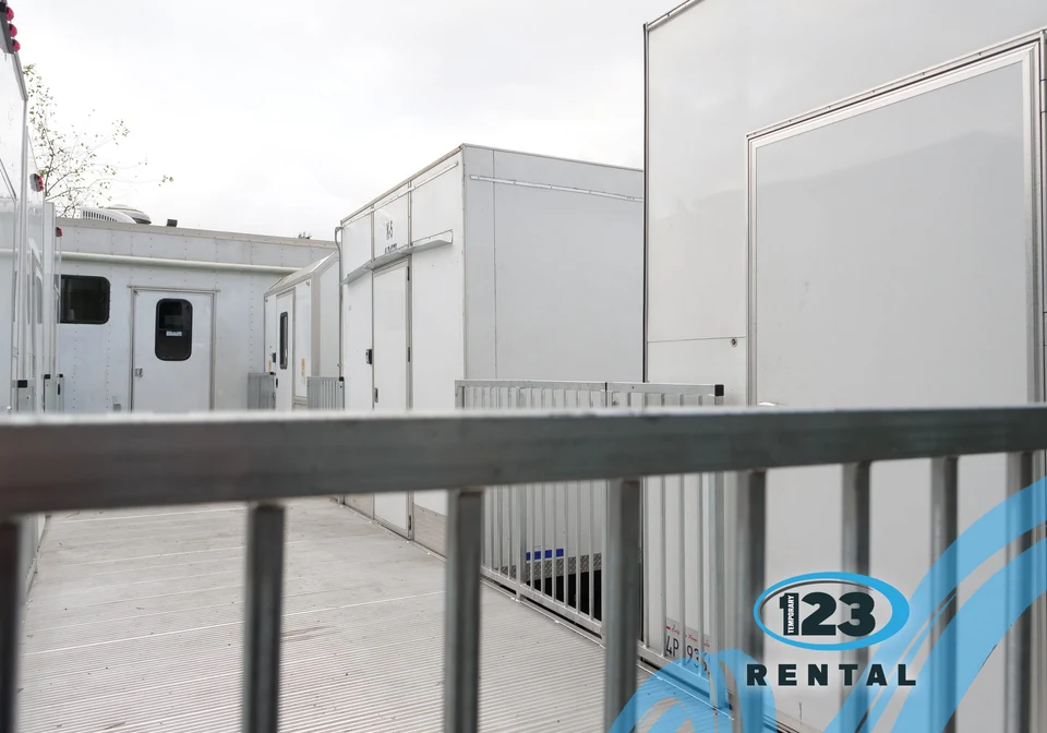 Raised access ramp and deck with railings beside temporary units